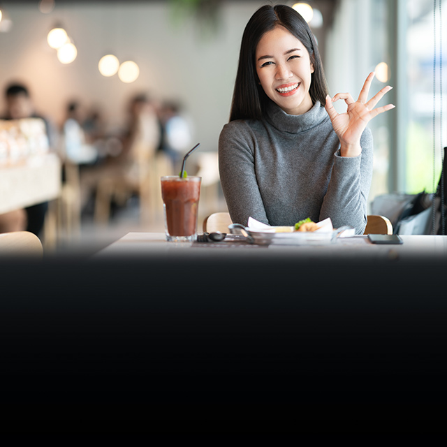 female smiling hand making ok sign in a cafe